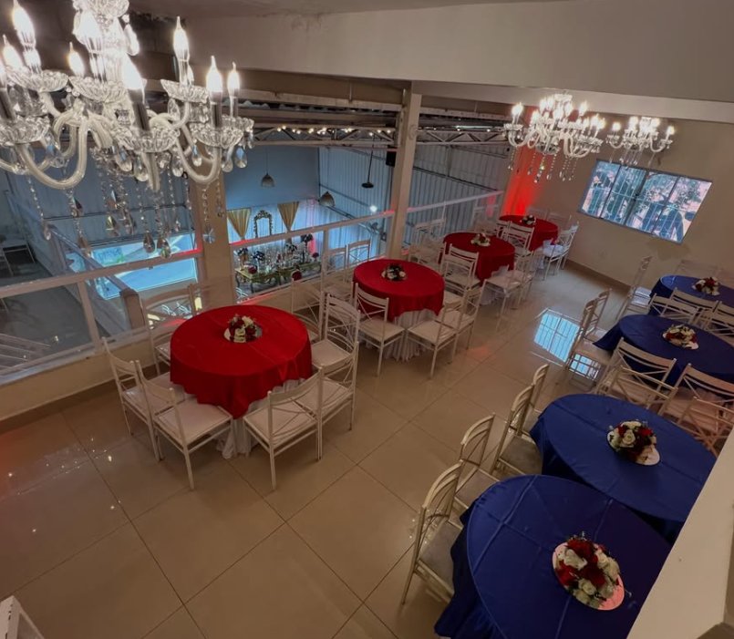Salão com mesas decoradas e lustres de cristal